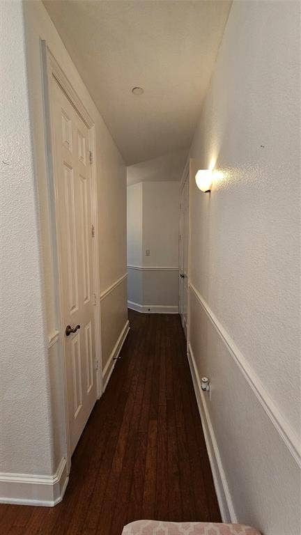 Hallway featuring wood-finish flooring, white paneled doors, wainscoting, wall sconce lighting, and recessed ceiling lighting