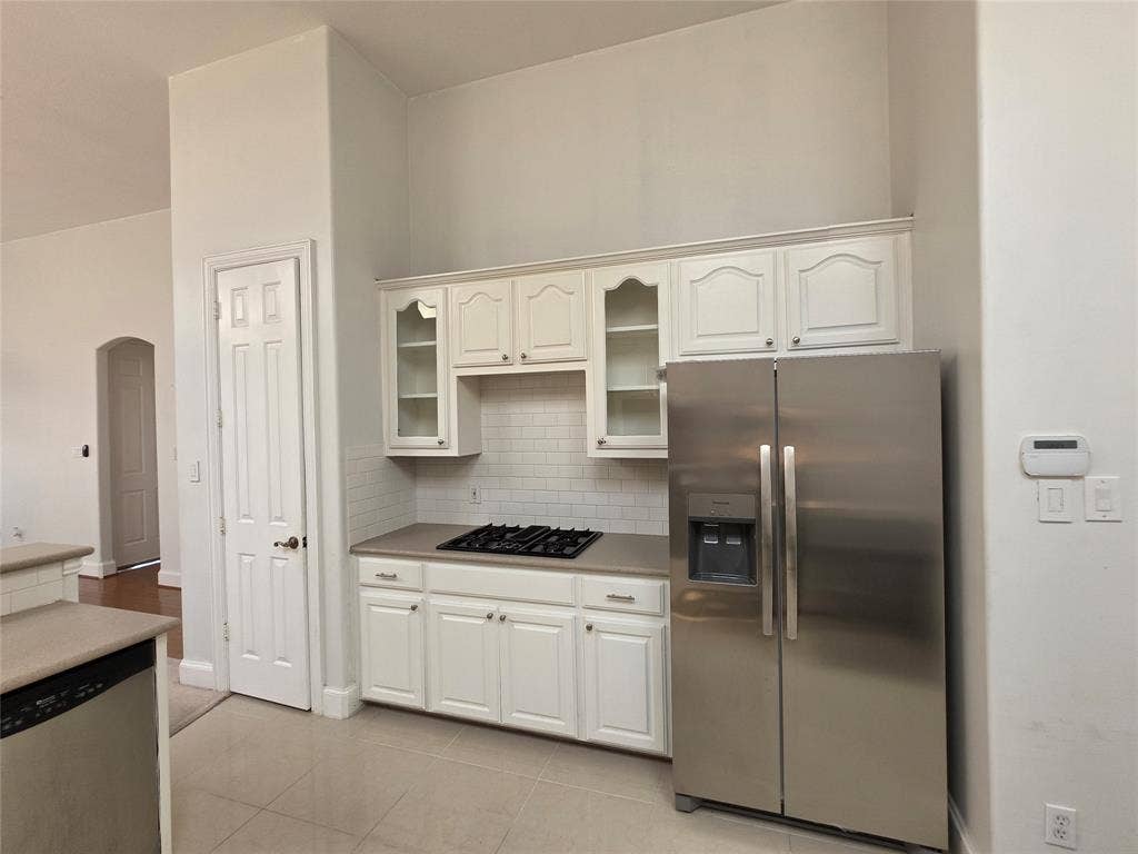 Kitchen featuring a stainless steel side-by-side refrigerator, white cabinetry, subway tile backsplash, and a built-in gas cooktop