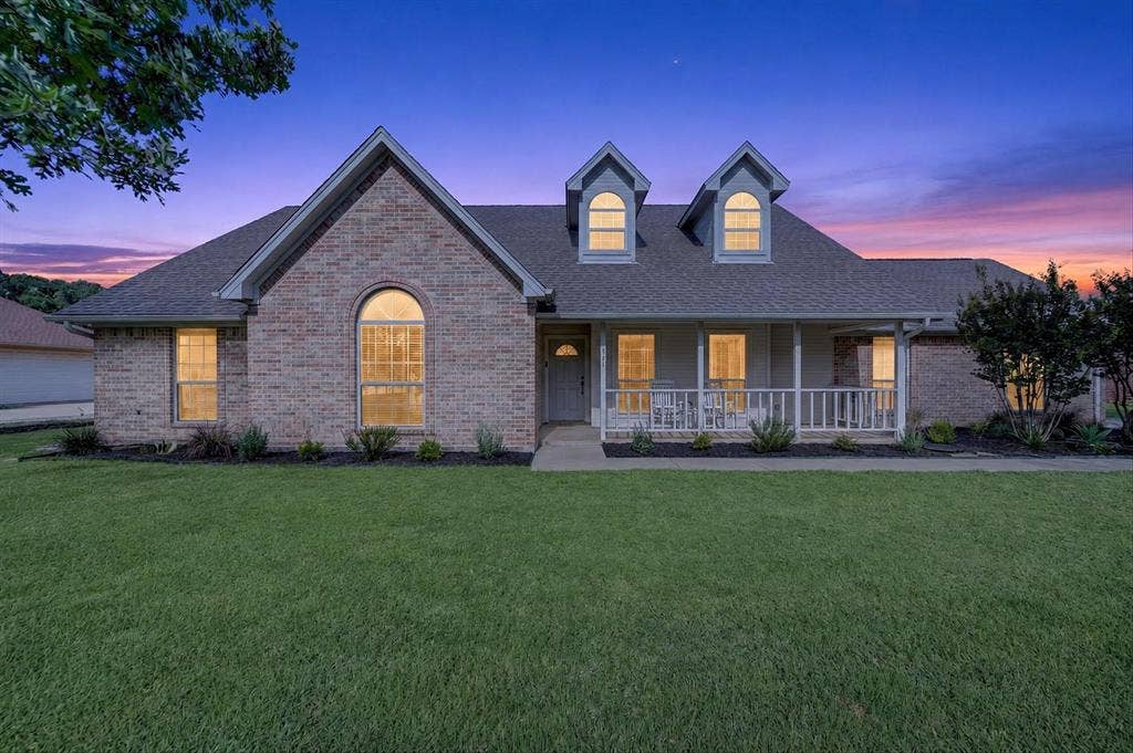 Brick exterior featuring a covered front porch with white railing