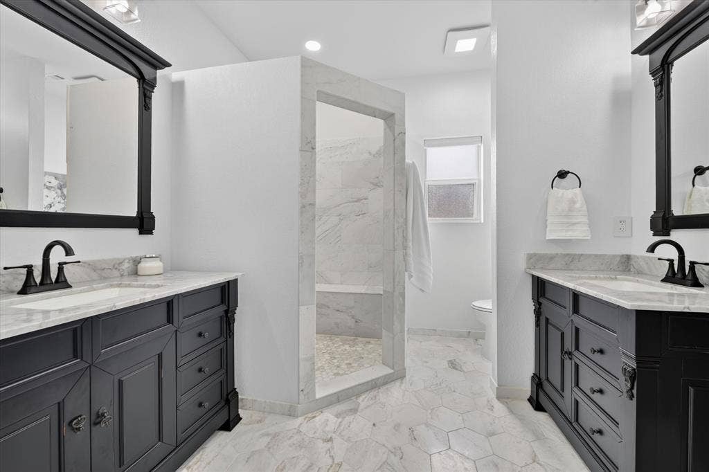 Dual vanity bathroom featuring black cabinetry, white countertops, and black framed mirrors