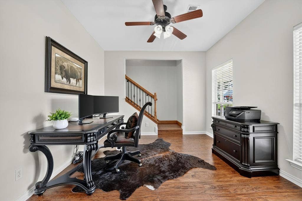 Bright interior room with wood-finish flooring, light-toned walls, and a ceiling fan