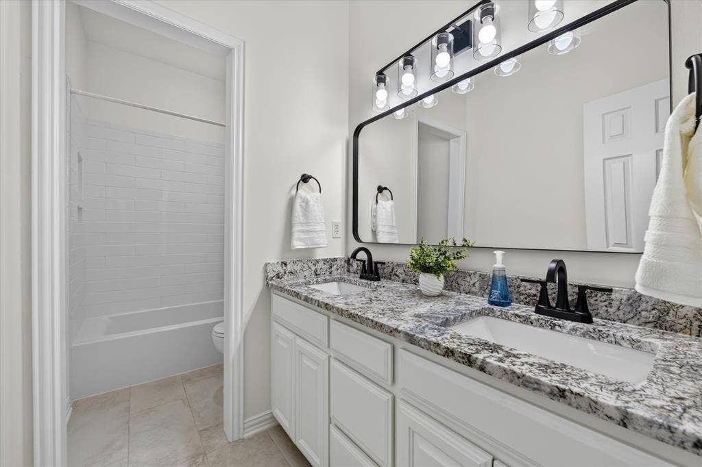 Dual sink vanity featuring granite countertops and matte black fixtures