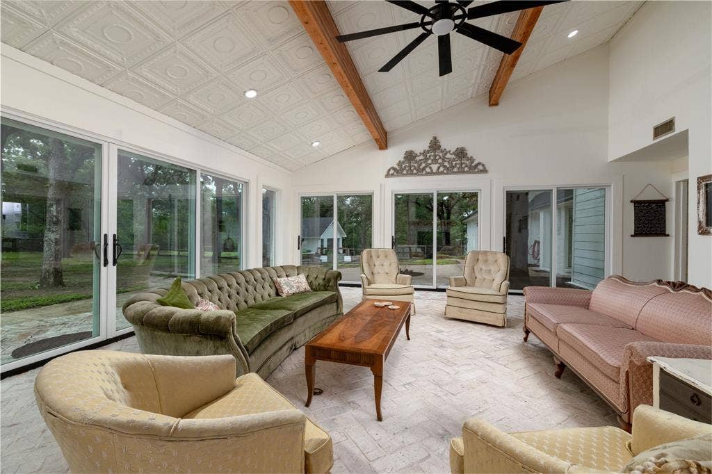 Spacious room featuring vaulted ceilings with exposed wood beams, a decorative pressed tin ceiling, and multiple sliding glass doors