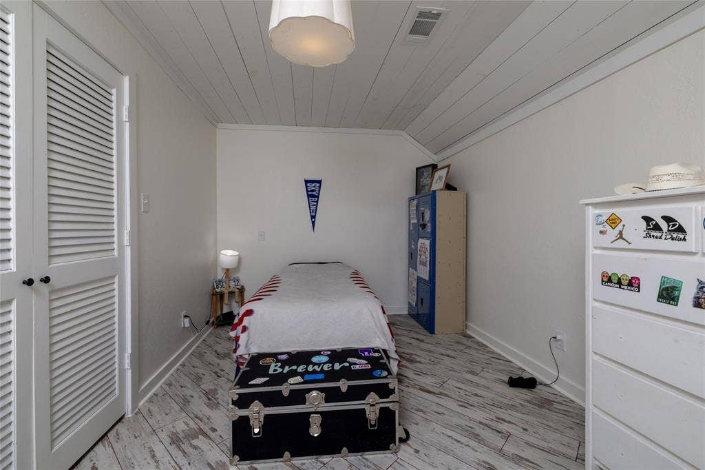 Attic room featuring white wood-finish flooring, white horizontal plank ceiling, and white louvered double doors