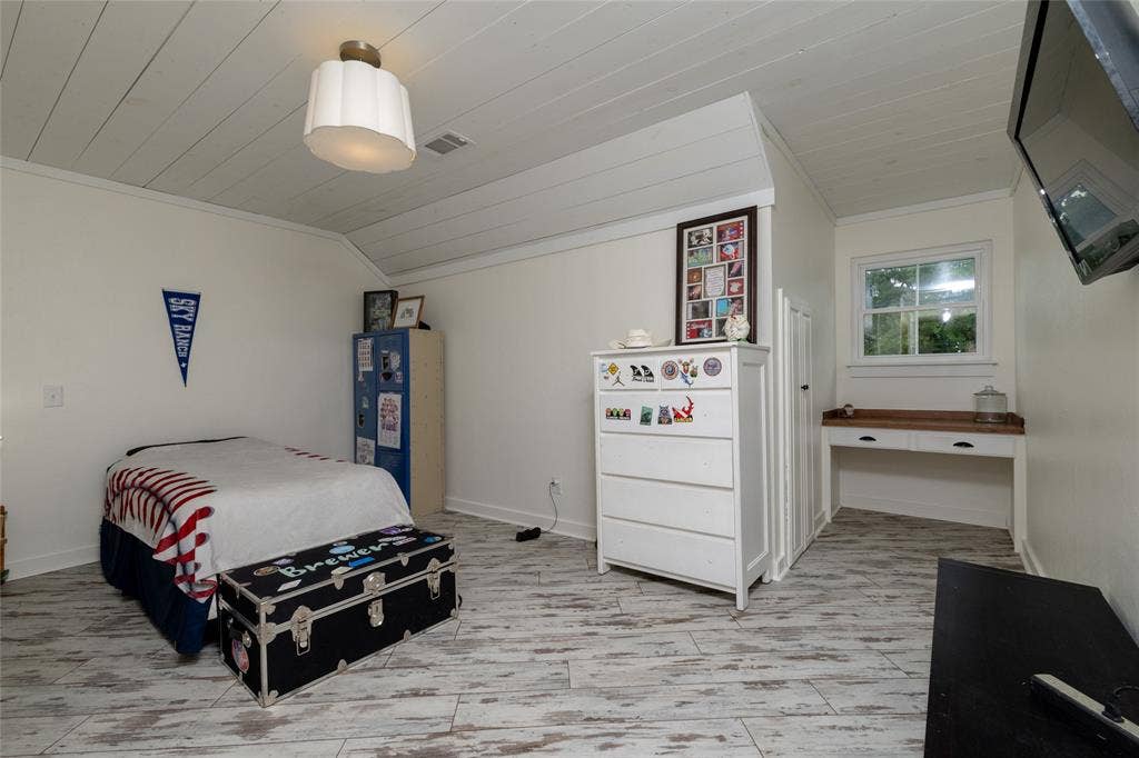 Room featuring white planked ceiling, wood-finish flooring, built-in window desk, window, and a wall-mounted light fixture