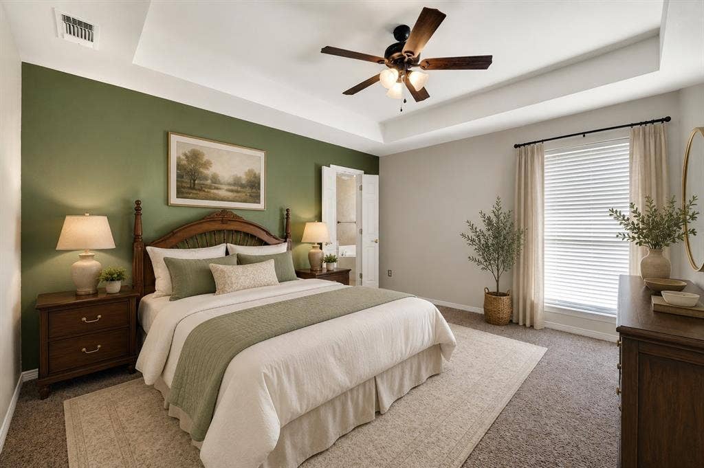 Spacious bedroom featuring a tray ceiling, ceiling fan, and carpeted flooring- Virtually Stages