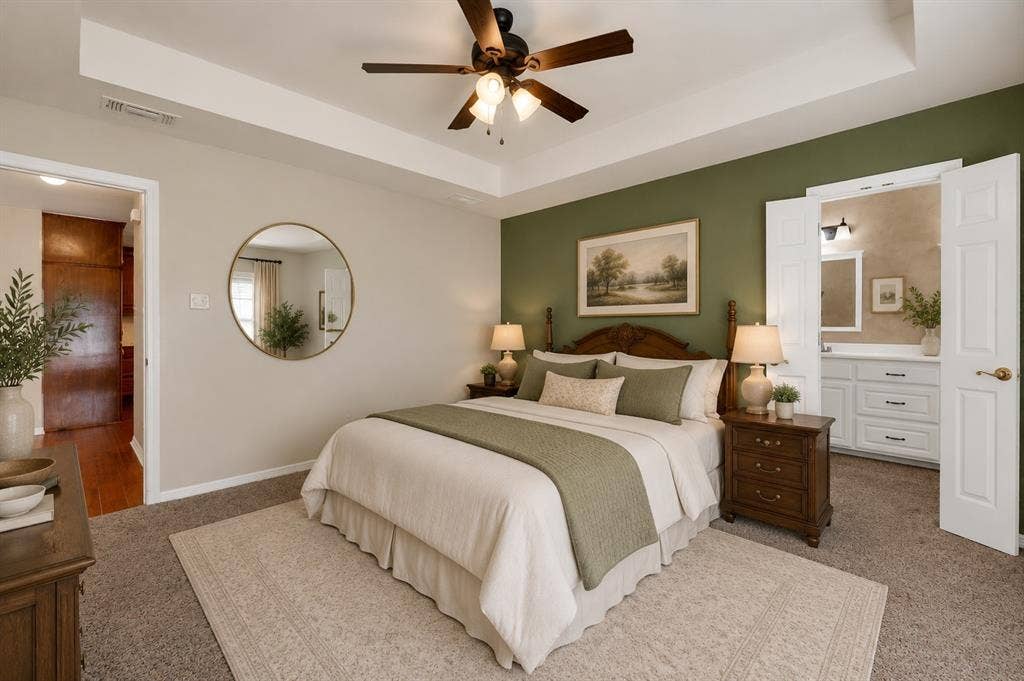 Bedroom featuring a tray ceiling, ceiling fan, and carpet flooring - Virtually Stages
