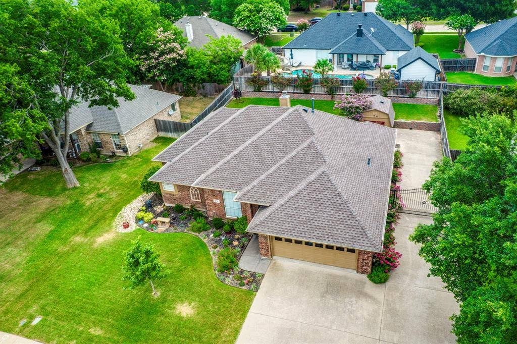 Brick exterior with a multi-gabled roofline, two-car garage, concrete driveway, and established landscaping