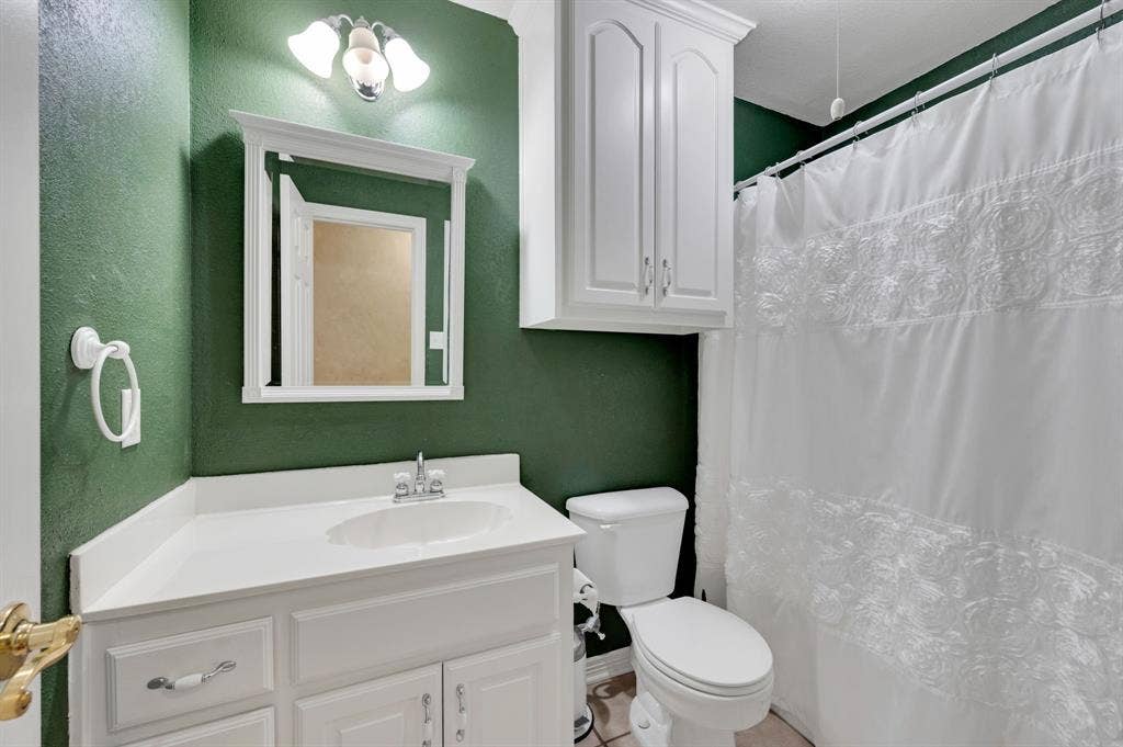 Bathroom featuring a white vanity with integrated sink, white cabinetry, and a full-size toilet