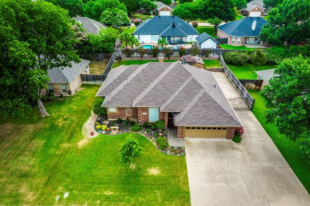 Brick exterior home featuring a concrete driveway, two-car garage, established landscaping, and a manicured lawn