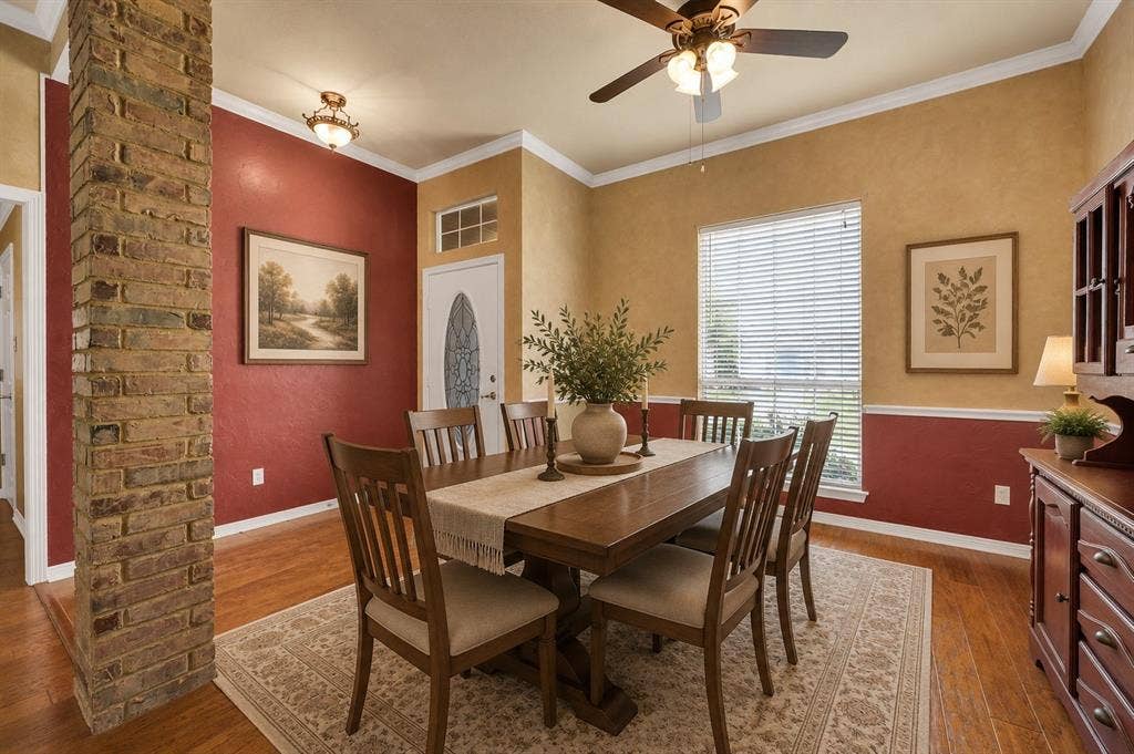 Dining space featuring wood-finish flooring, two-tone wall treatment, and crown molding - Virtually Stages