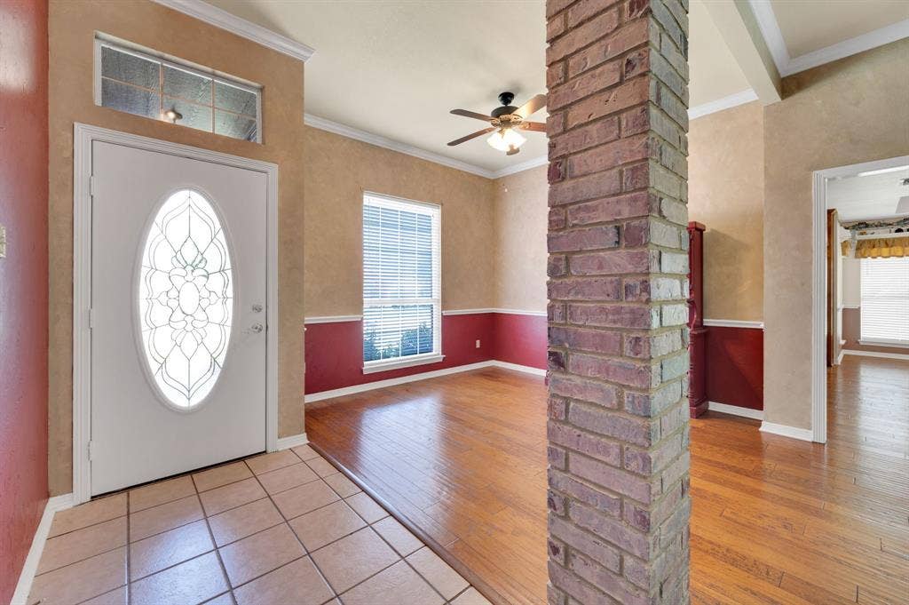 Entryway featuring a decorative oval-inset front door, a transom window, and tile flooring