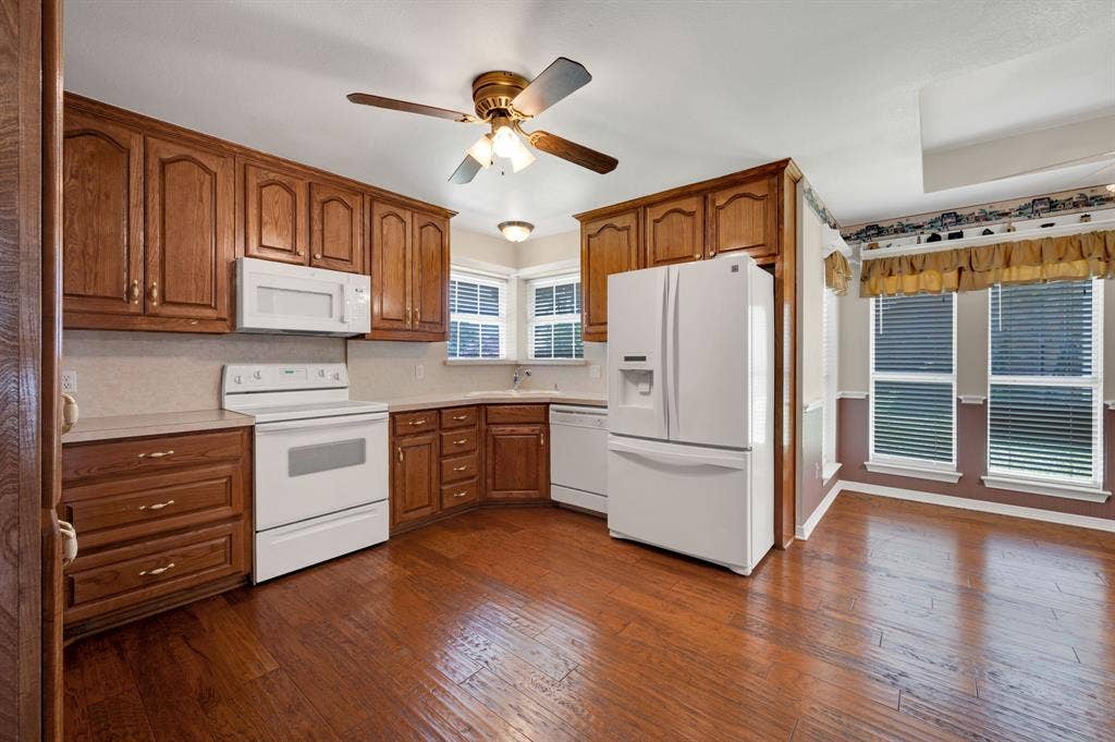 Kitchen featuring wood-finish flooring, wood cabinetry, white appliances, recessed lighting, and a ceiling fan