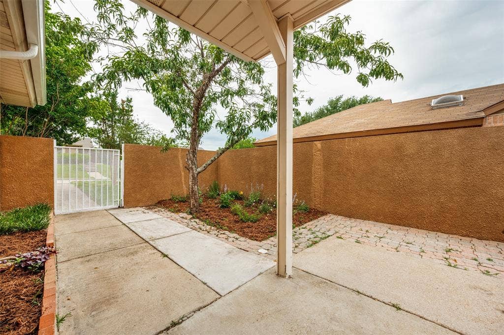 412 Pogue Street, Cedar Hill, TX 75104 Covered patio area featuring concrete and paver flooring, stucco privacy walls, and a secure gated entry