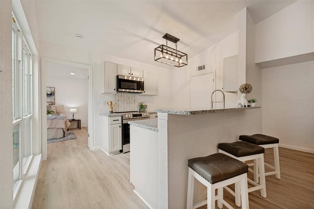 412 Pogue Street, Cedar Hill, TX 75104 Kitchen featuring light wood-finish flooring, white cabinetry, stainless steel appliances, and a mosaic tile backsplash