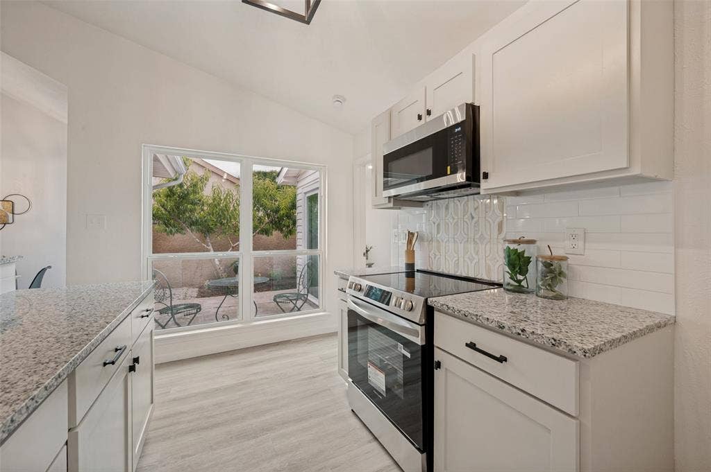 412 Pogue Street, Cedar Hill, TX 75104 Kitchen featuring light-finish cabinetry, granite-finish countertops, stainless steel appliances, a subway tile backsplash, and wood-finish flooring
