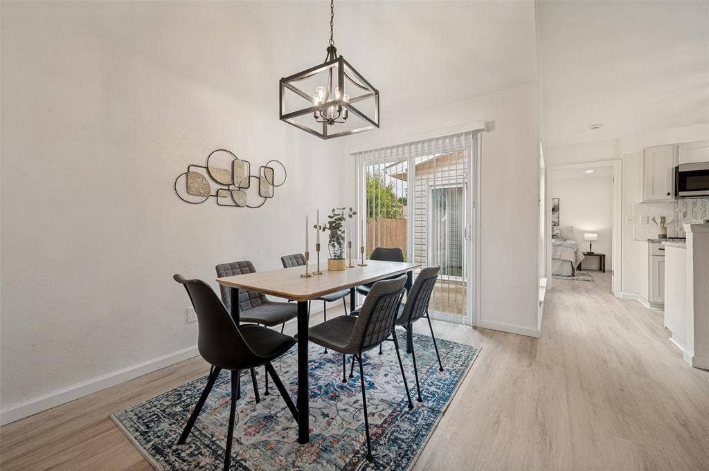 412 Pogue Street, Cedar Hill, TX 75104 Dining area featuring light wood-finish flooring, a contemporary chandelier, and sliding glass doors with vertical blinds