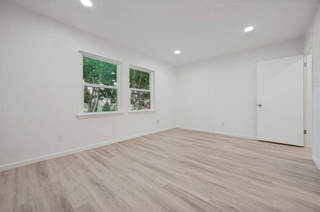 412 Pogue Street, Cedar Hill, TX 75104 Spacious room featuring light wood-finish flooring, recessed lighting, white walls, white trim, and two double-hung windows