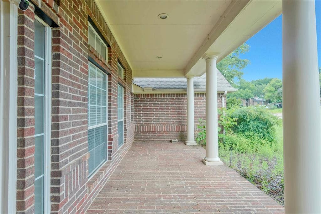 front yard Covered front porch featuring a brick-patterned paver surface