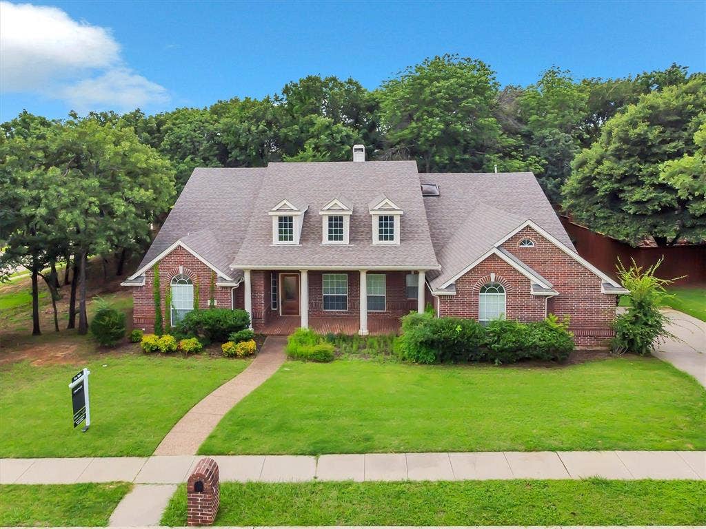 Traditional brick residence featuring a gabled roofline and multiple dormer windows