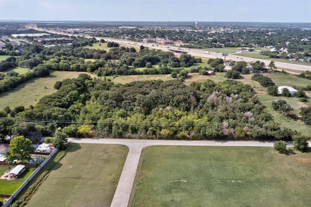 Expansive land parcel featuring a mature tree canopy, flat topography, and clear access road