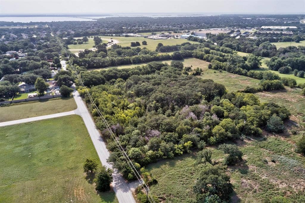 Expansive land parcel featuring mature trees, open clearings, and direct road frontage