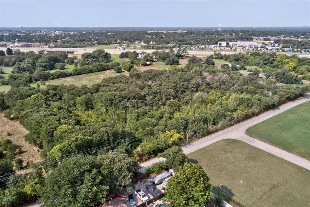 Expansive wooded lot featuring a paved road frontage and scattered mature trees