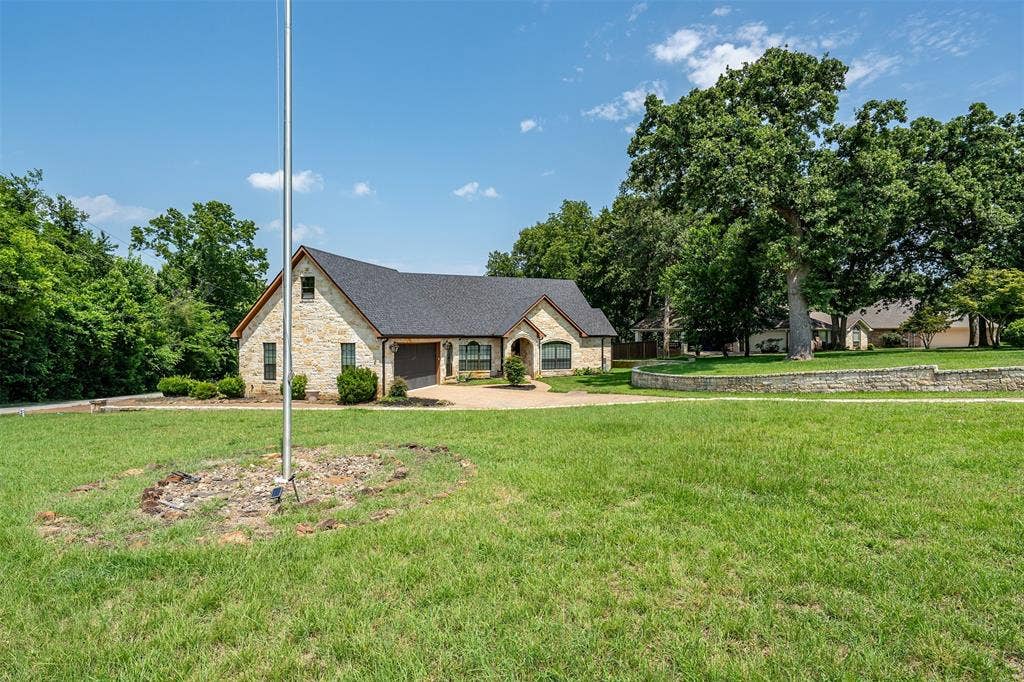 6414 Dorsey Drive, Athens, TX 75752 Stone-clad exterior featuring a gabled roofline and attached garage