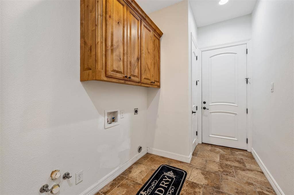 6414 Dorsey Drive, Athens, TX 75752 Laundry area with warm wood cabinetry, neutral wall paint, and patterned tile flooring