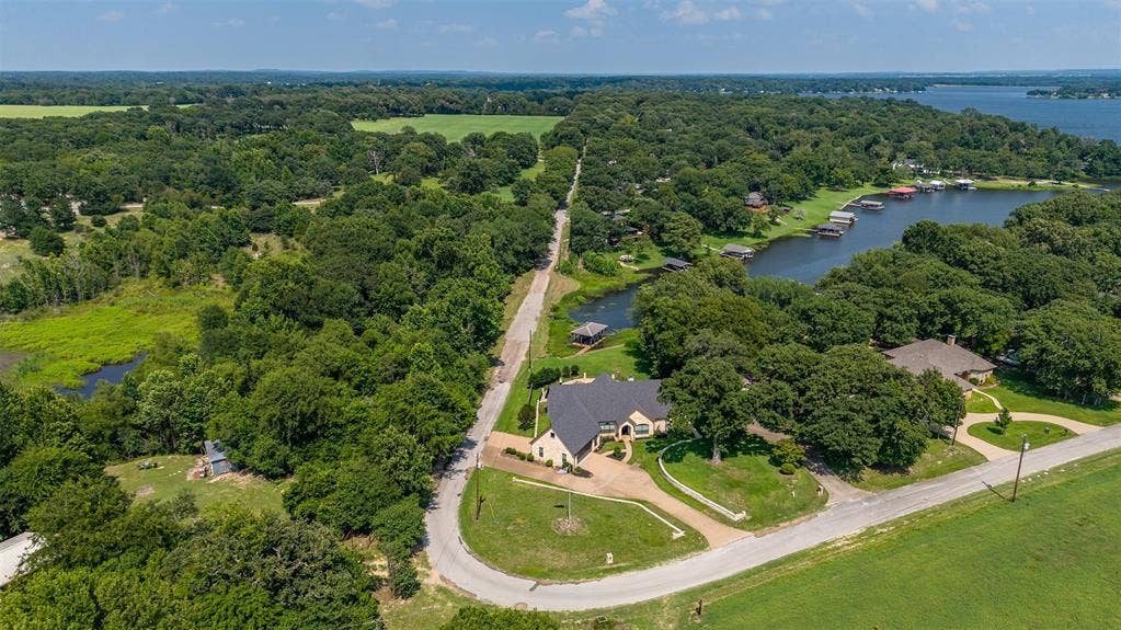 6414 Dorsey Drive, Athens, TX 75752 Expansive property featuring a curved driveway, mature trees, and a distant body of water