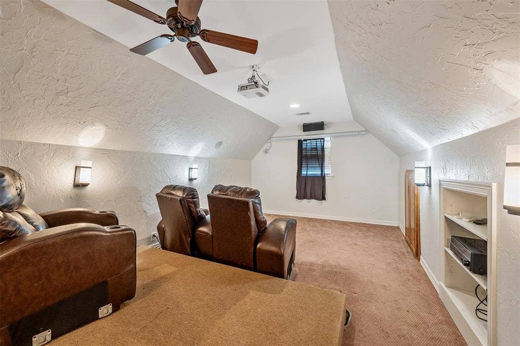 6414 Dorsey Drive, Athens, TX 75752 Carpeted entertainment space featuring sloped ceilings, ceiling fan, wall sconces, projector, and built-in shelving