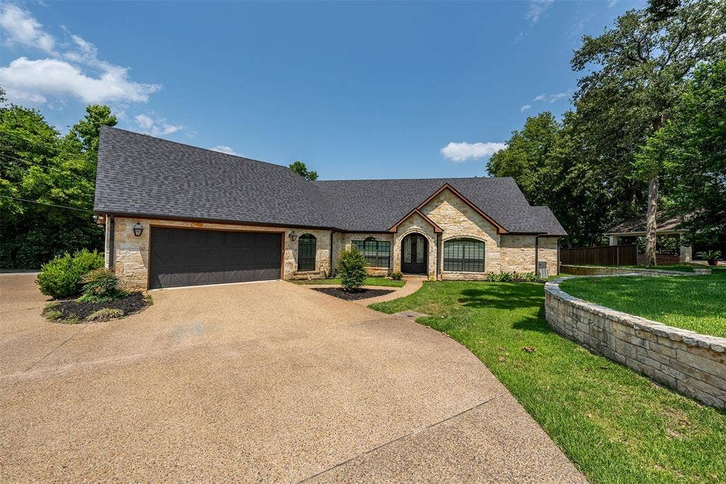 6414 Dorsey Drive, Athens, TX 75752 Stone facade residence featuring an expansive driveway, a two-car garage, and a dark shingle roof