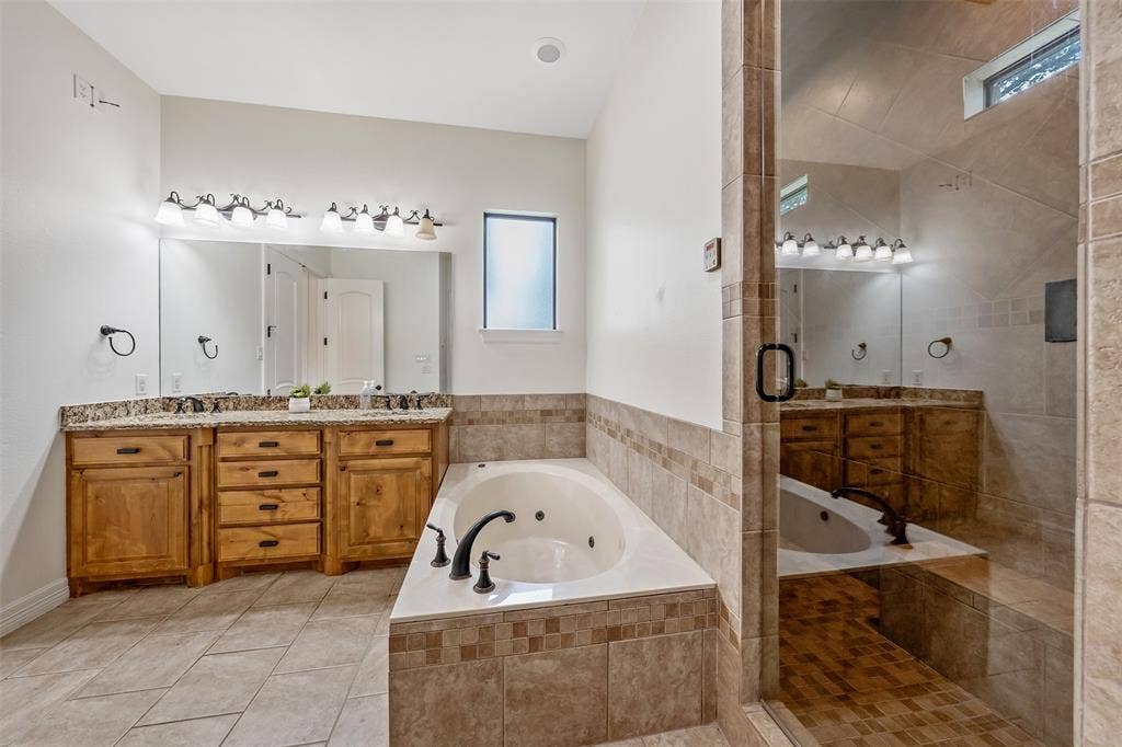 6414 Dorsey Drive, Athens, TX 75752 Bathroom featuring a jetted soaking tub, a tiled walk-in shower with a glass enclosure, dual vanity with wood cabinetry and stone countertops, and tile flooring