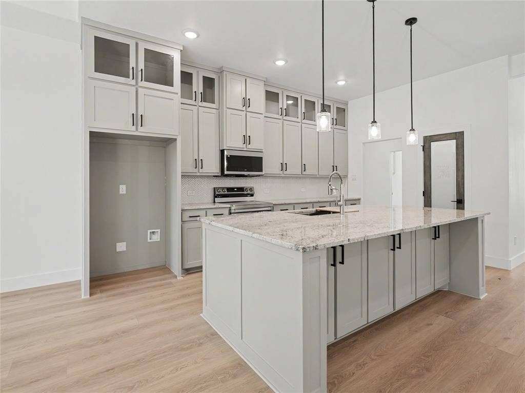 113 Dennis Drive, Azle, TX 76020 Open-concept kitchen featuring an expansive central island with a light-colored countertop, light gray cabinetry, and a subway tile backsplash