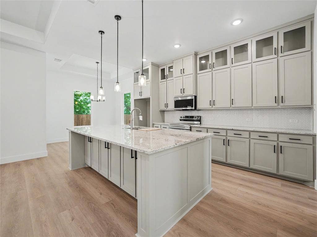 113 Dennis Drive, Azle, TX 76020 Gourmet kitchen featuring a large island, light-toned cabinetry, granite countertops, wood-finish flooring, and pendant lighting