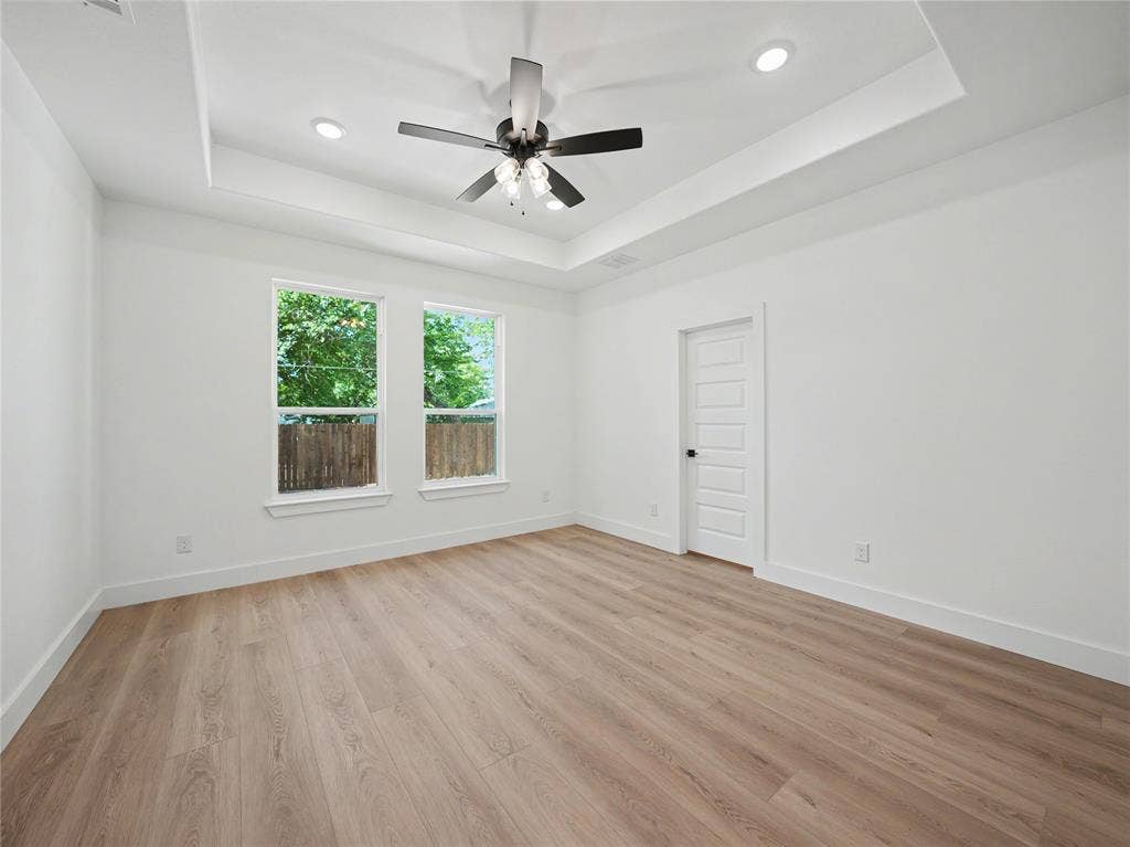 113 Dennis Drive, Azle, TX 76020 Spacious room featuring wood-finish flooring, a tray ceiling with recessed lighting and a ceiling fan, and two large windows offering natural light