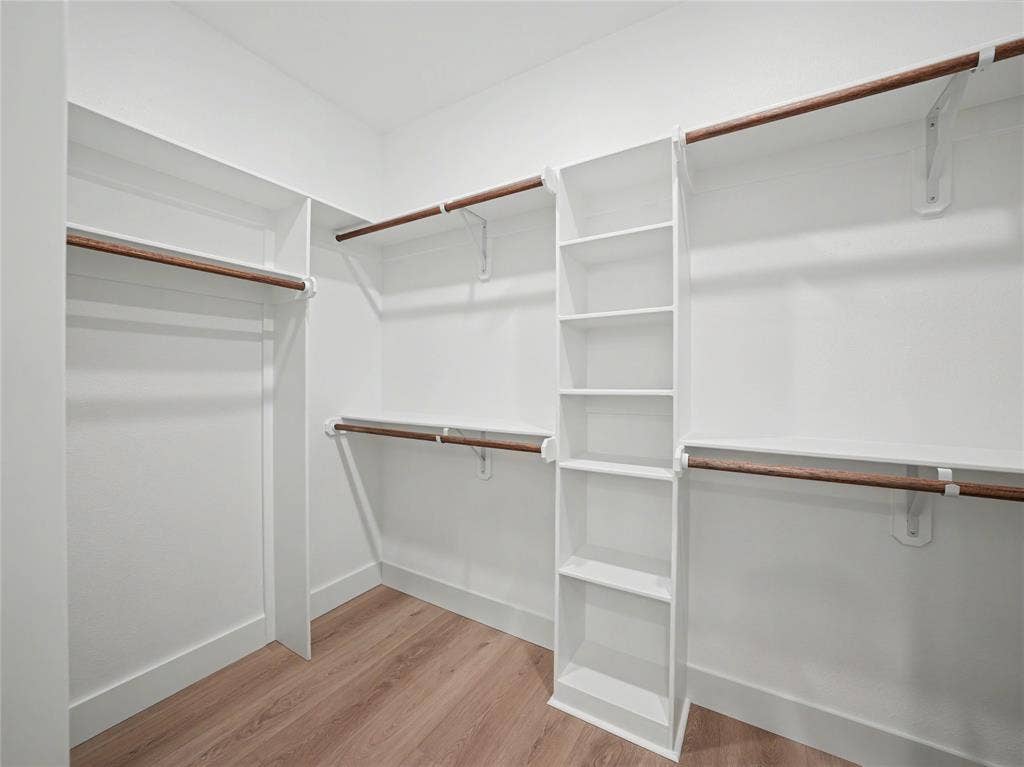 113 Dennis Drive, Azle, TX 76020 Walk-in closet featuring built-in shelving, multiple hanging rods, white walls, and wood-finish flooring