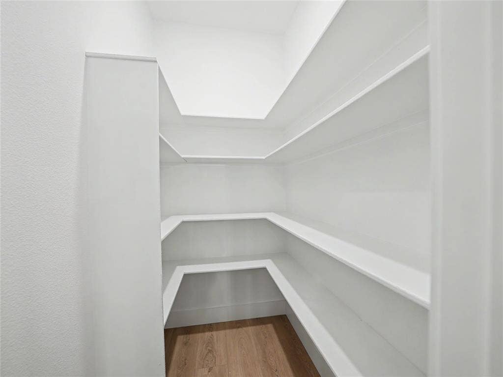 113 Dennis Drive, Azle, TX 76020 Spacious pantry featuring multiple tiers of built-in shelving, white walls, and wood-finish flooring