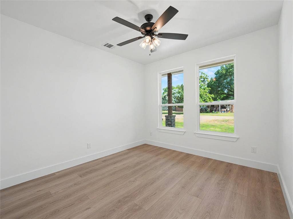 113 Dennis Drive, Azle, TX 76020 Light-filled interior space featuring two windows, wood-finish flooring, and a ceiling fan with integrated lighting