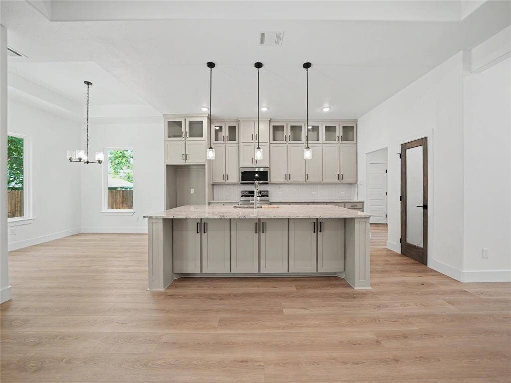 113 Dennis Drive, Azle, TX 76020 Open-concept kitchen featuring a large central island with a light-toned countertop, grey shaker-style cabinetry, and three pendant lights