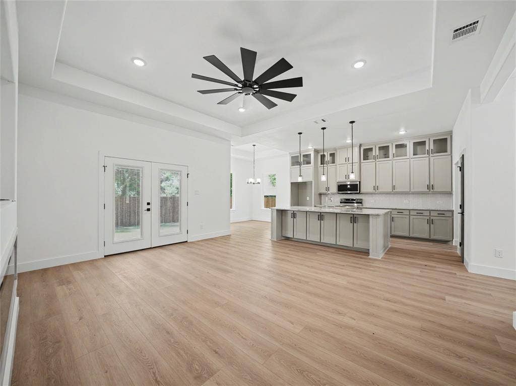 113 Dennis Drive, Azle, TX 76020 Open-concept living space featuring light wood-finish flooring, a tray ceiling with a contemporary ceiling fan, and recessed lighting