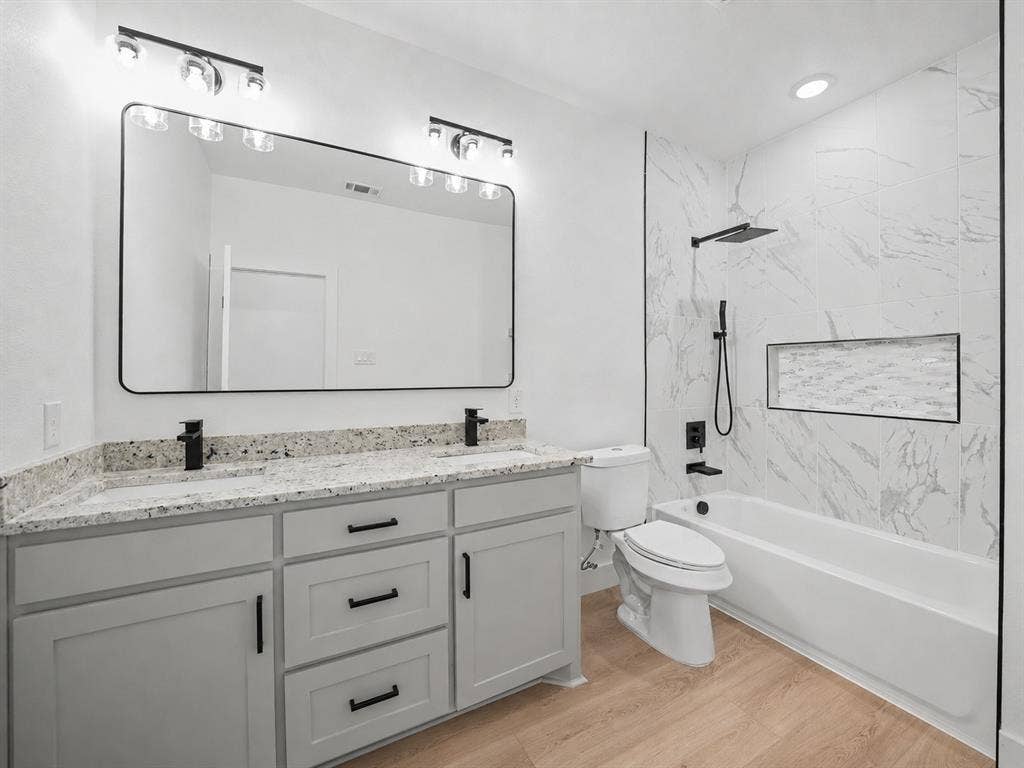 113 Dennis Drive, Azle, TX 76020 Bathroom featuring a double vanity with granite-style countertops, light wood-finish flooring, a full bathtub with a shower niche, and matte black fixtures