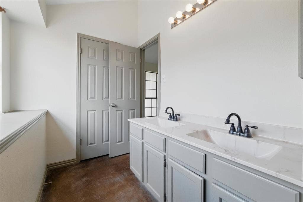 Bathroom with finished concrete flooring and double vanity