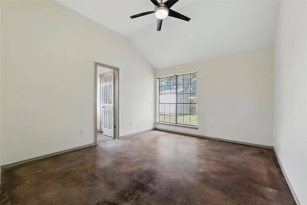 Spare room with concrete flooring, a ceiling fan, baseboards, and lofted ceiling