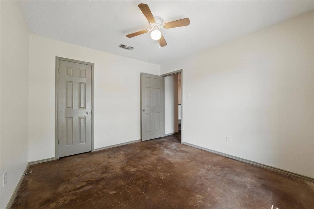 Unfurnished bedroom with unfinished concrete floors, baseboards, and a ceiling fan