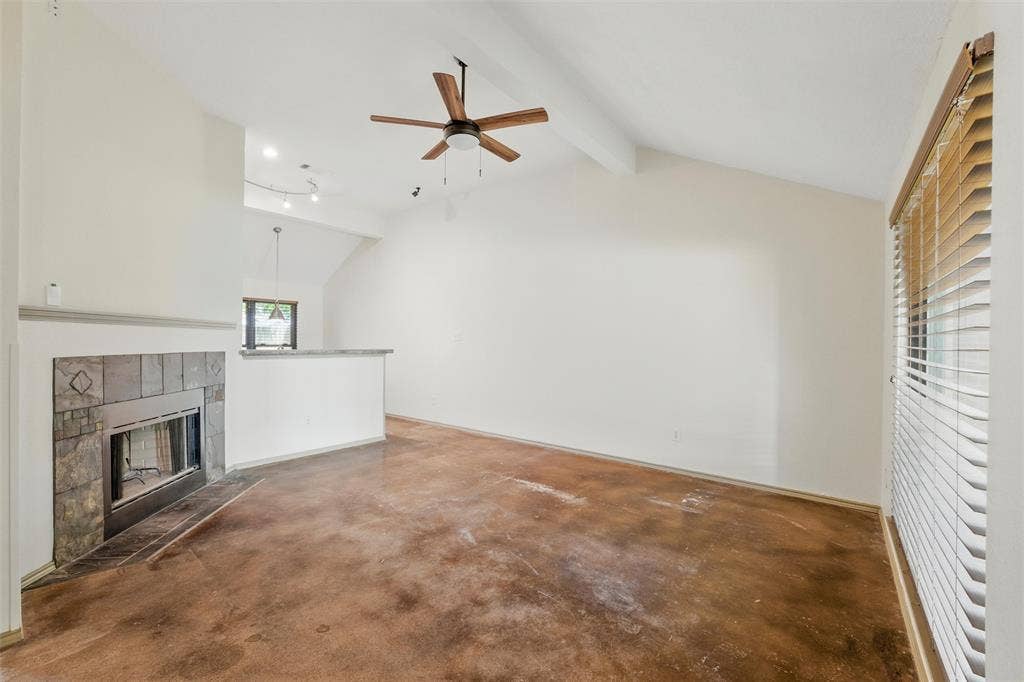 Unfurnished living room with a ceiling fan, concrete floors, and a tiled fireplace