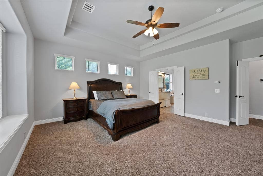 Spacious room featuring tray ceiling, ceiling fan, neutral wall paint, and plush carpeting