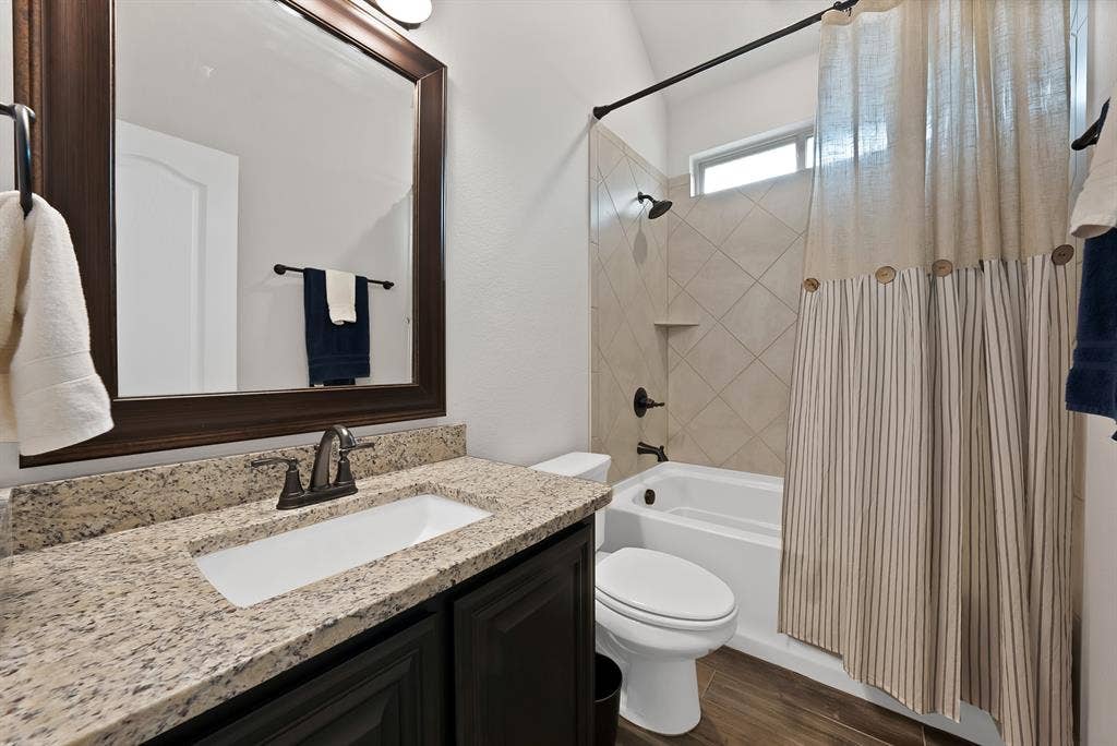 Bathroom featuring a vanity with a granite-style countertop, dark wood-finish cabinetry, and an undermount sink