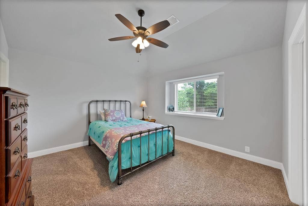 Carpeted room featuring a ceiling fan with integrated lighting, a window with blinds, and light gray walls