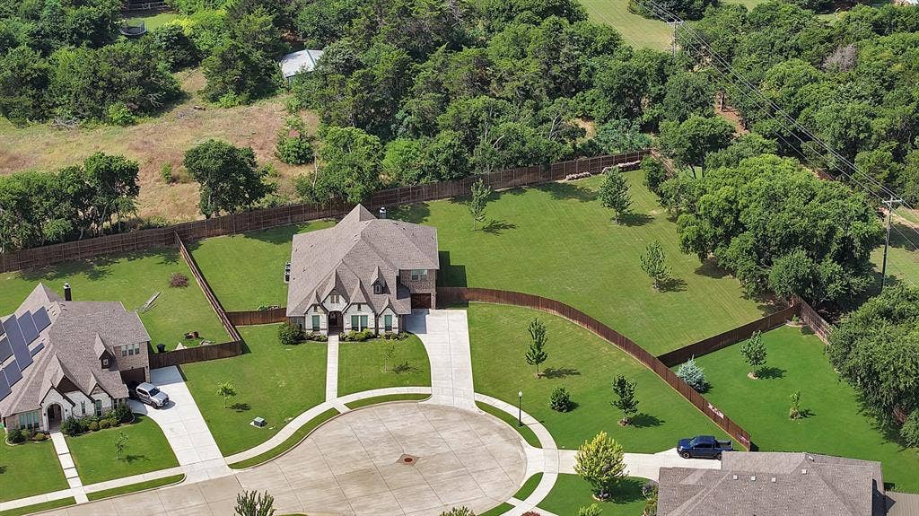 Suburban residential property featuring a large two-story home with a multi-gabled roofline and stone and siding facade